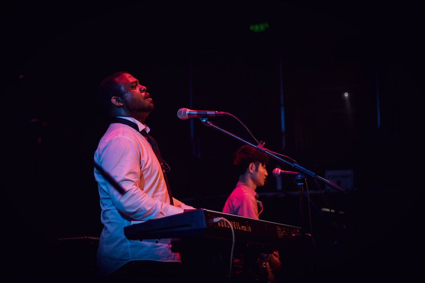 RAHAM singing and playing keyboards under red stage light