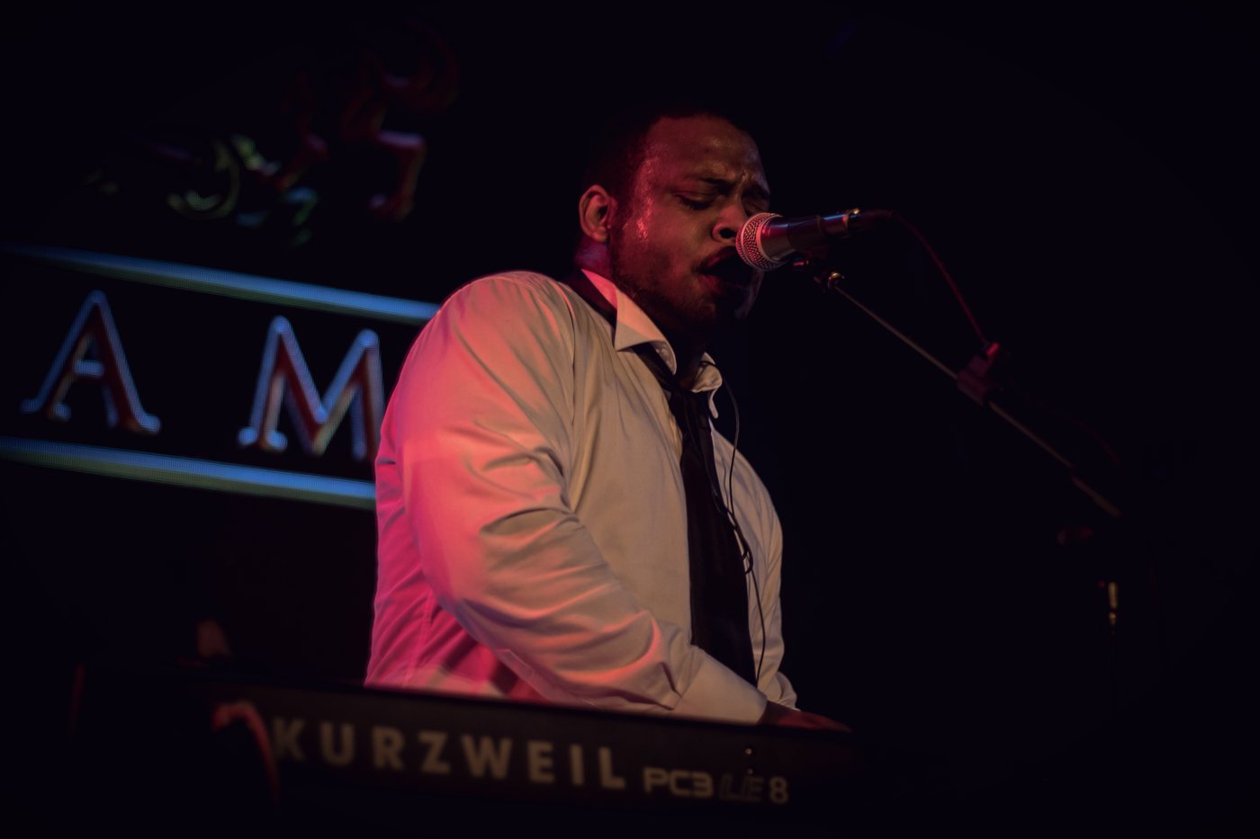 RAHAM singing into a microphone at the keyboard