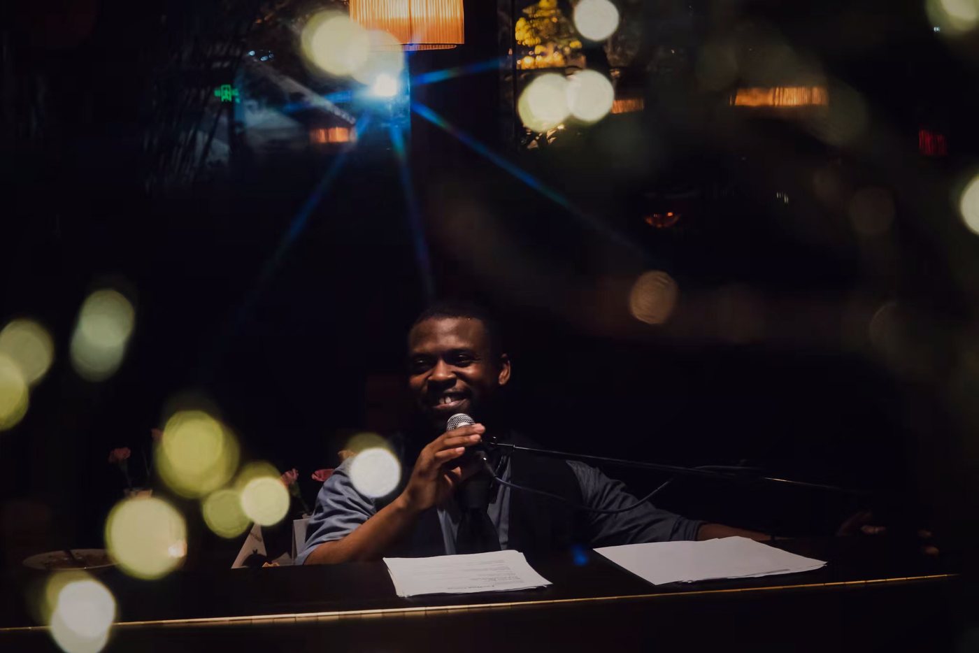 RAHAM at the piano at night with lights glowing behind