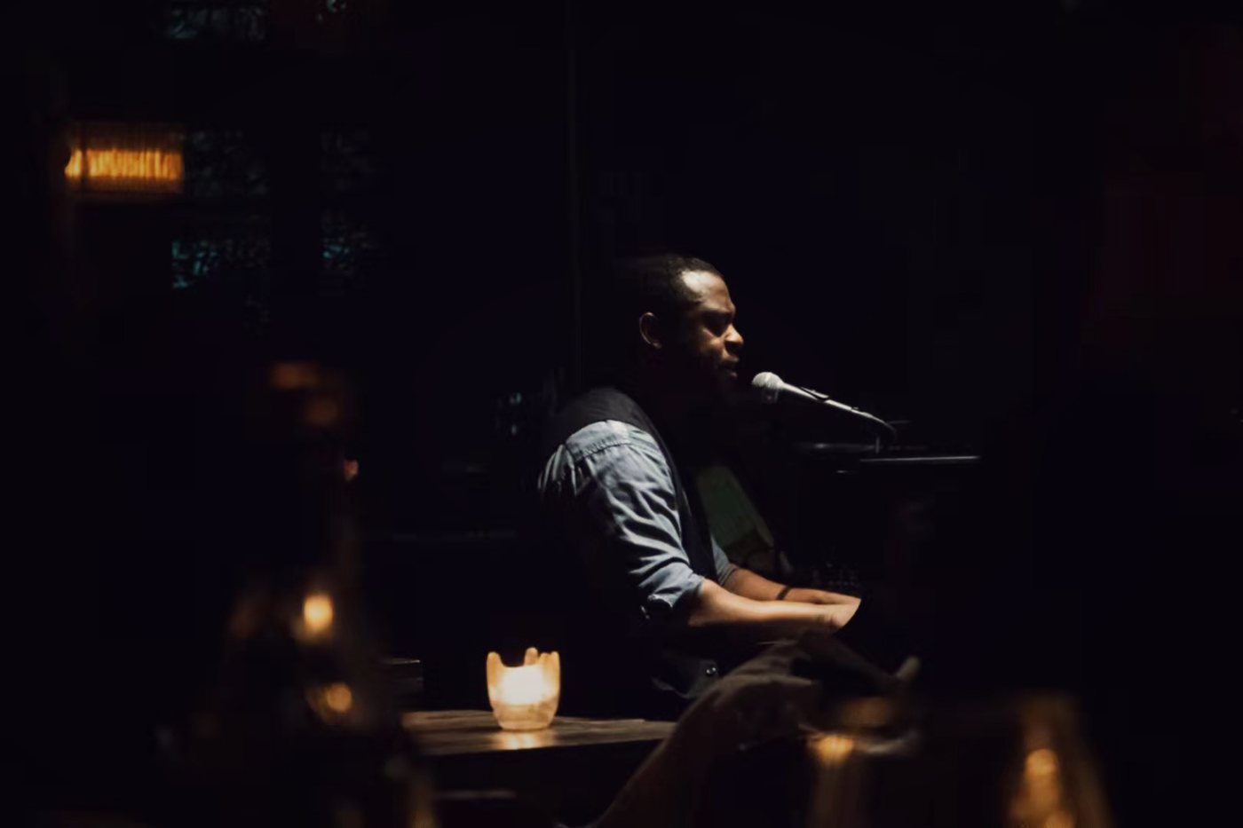 RAHAM at the piano in a dark venue lit by candlelight